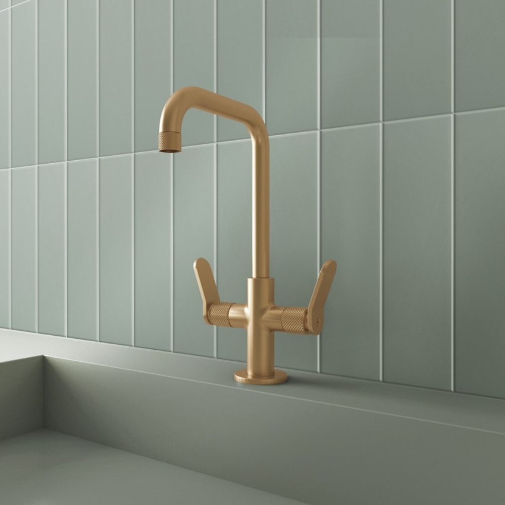 Lifestyle image of the Crosswater Calix Brushed Brass Tall Basin Mixer mounted on the deck of a green basin